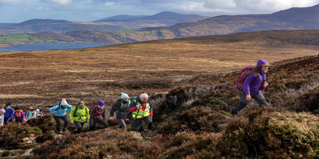 Brown hiking trail, group walking up mountain wearing bright jackets