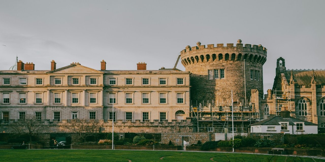 Vintage Dublin Castle with architectural groves and curves. Bright green grass in the foreground. 