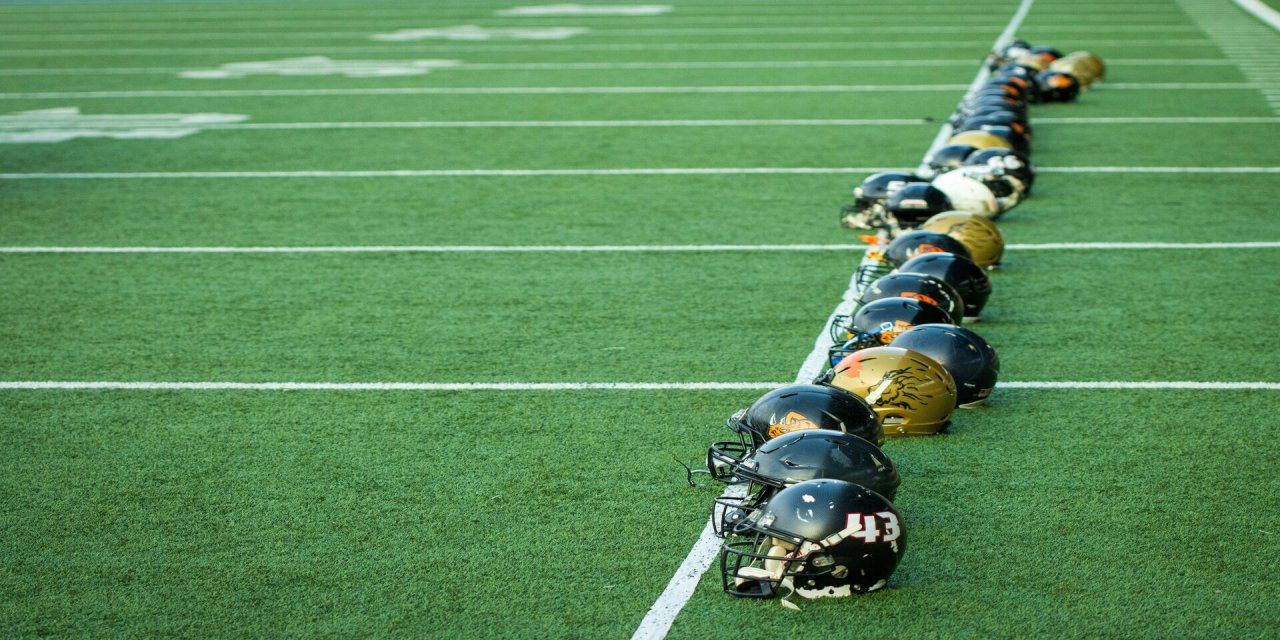 american football helmets lined up on field