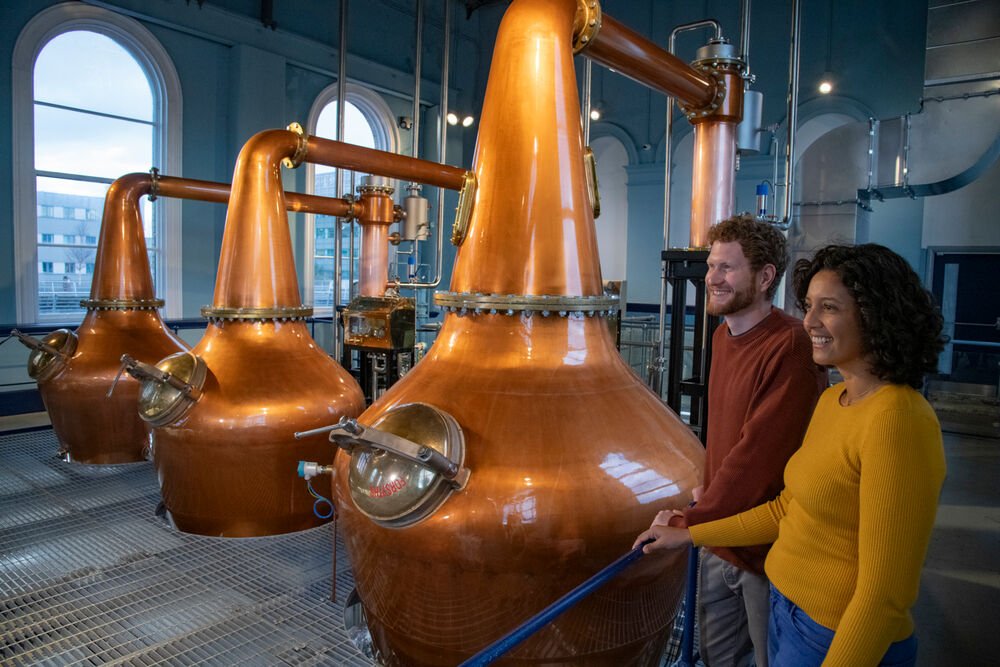 two people looking at whiskey distilling equipment