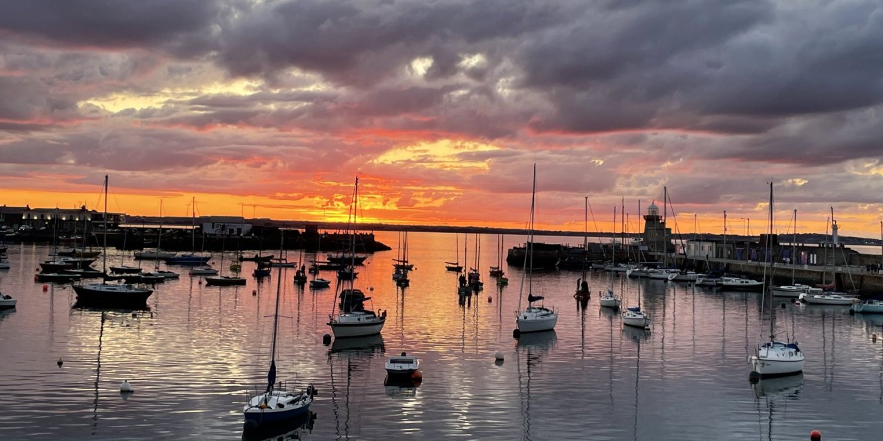 Boats docked at howth harbour while the sun sets 