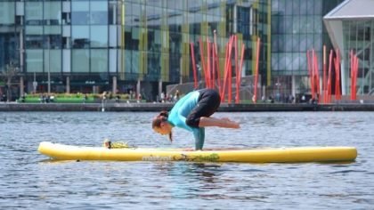 Lady practising yoga on stand up paddle board in grand canal basin dublin