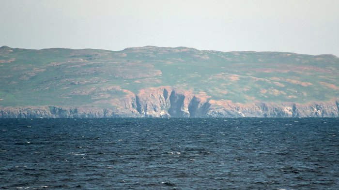 green land with cliff face beside water