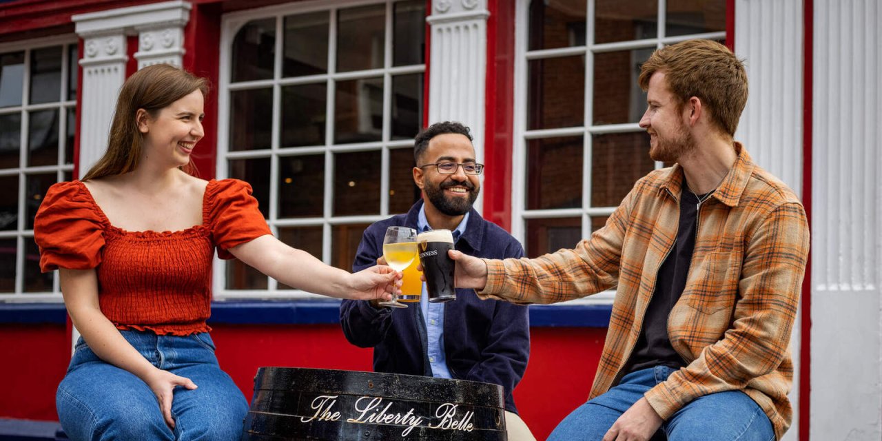 three people outside bar cheers 