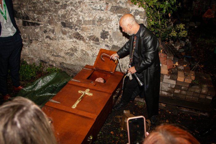 Image of scary man in graveyard beside a coffin.