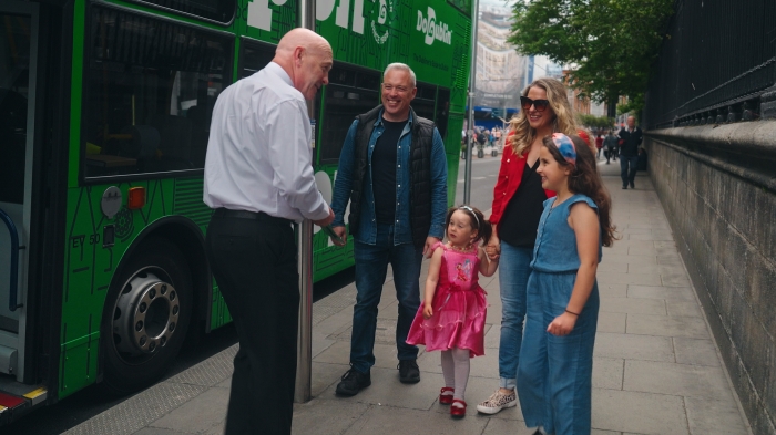 family of four standing on the path talking to a bus driver 