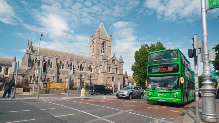 the hop on hop off bus driving through dublin and a church in the background