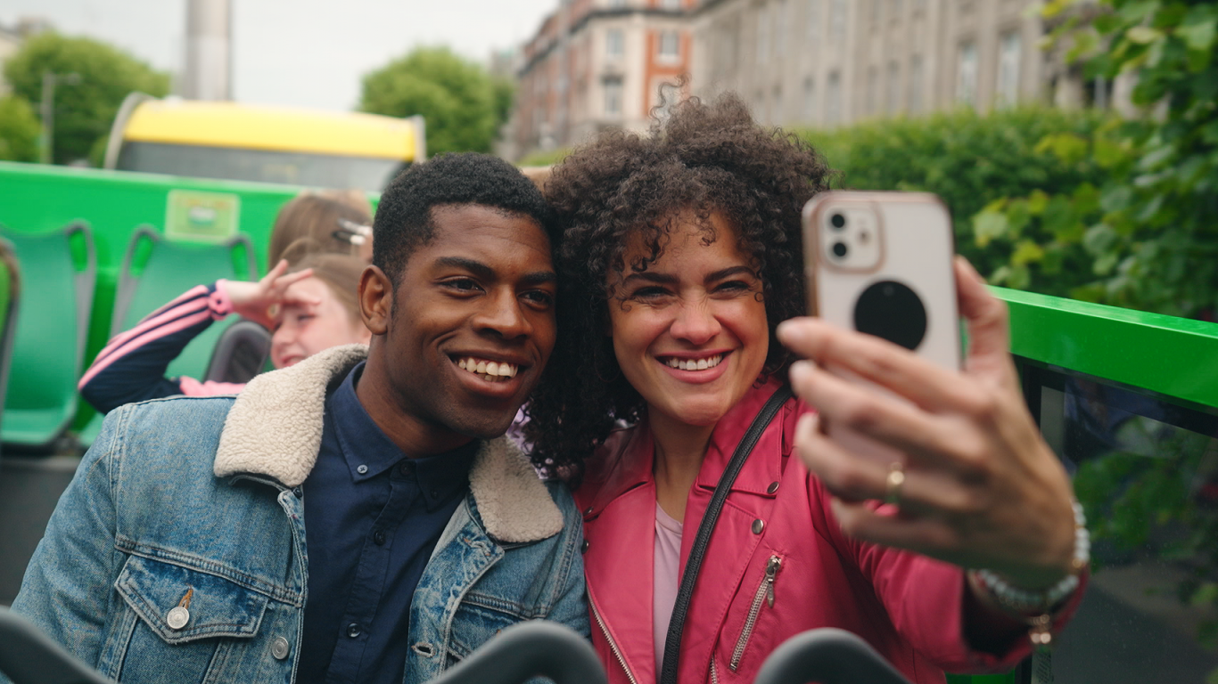 woman and a man taking a selfie on her mobile phone while on the open top bus 