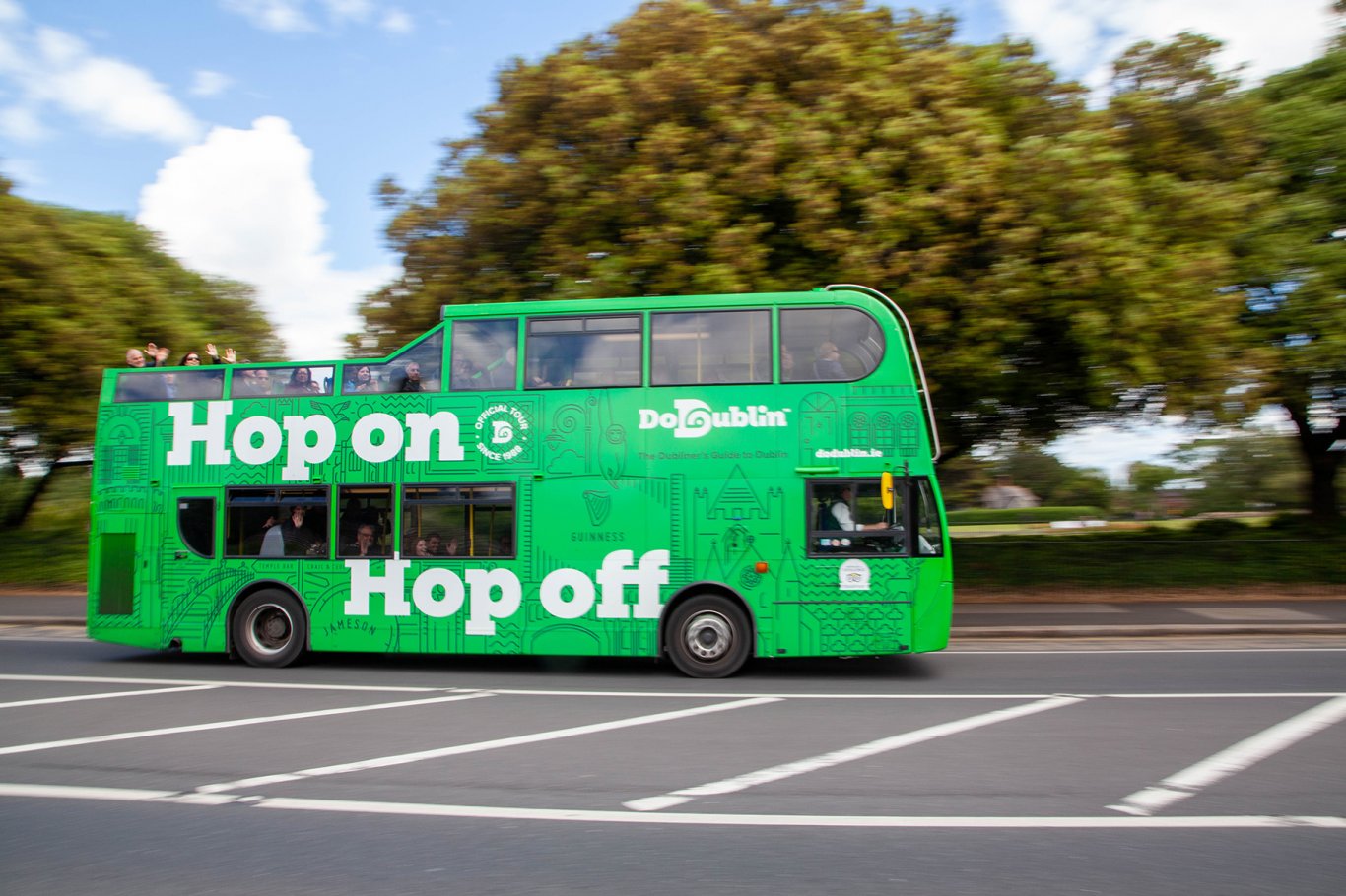 Passengers waving from open top tour bus