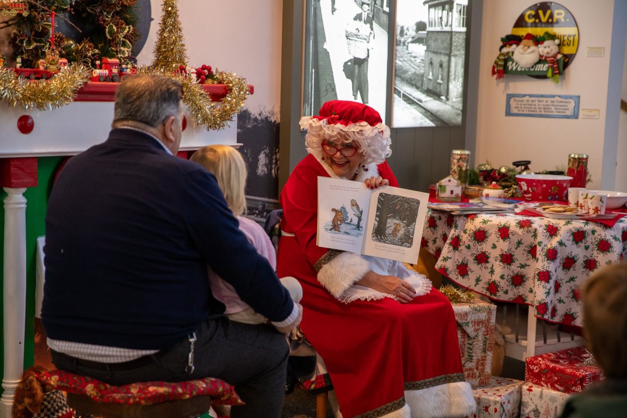 man and child with woman in red holding a book