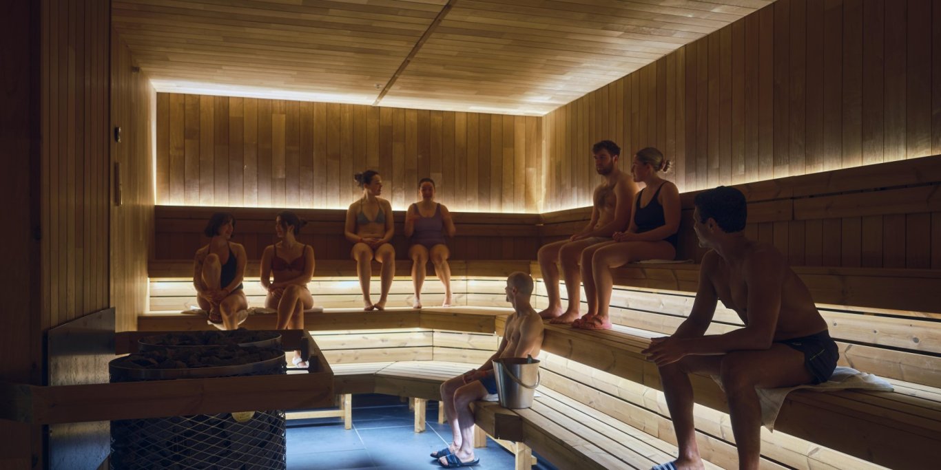 Hotbox Sauna with People Wooden sauna with built in led lights. People sitting on benches enjoying the heat.