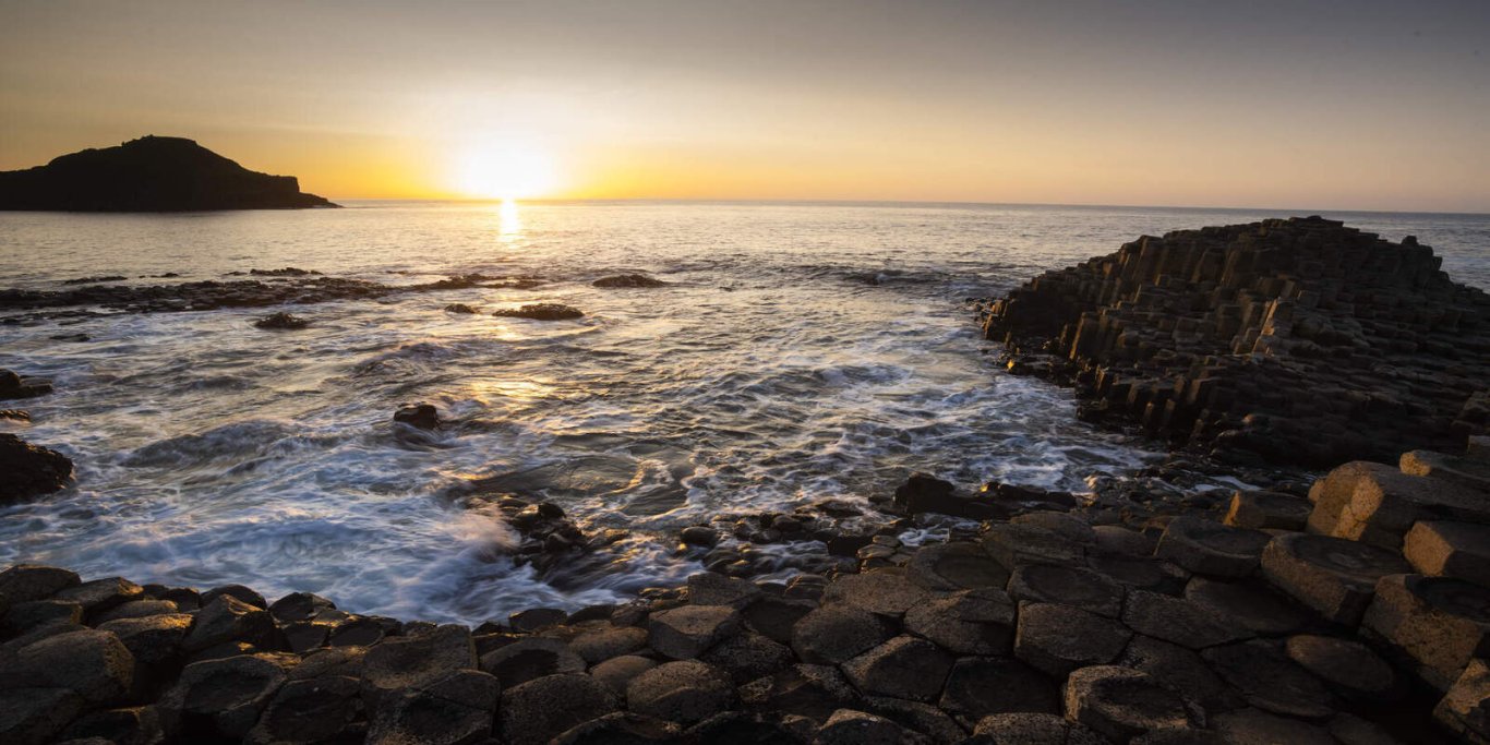giants-causeway-at-sunset_tourism-ireland-photographed-by-chris-hill Bright orange sunset with blue waves crashing against brown, dark rocks