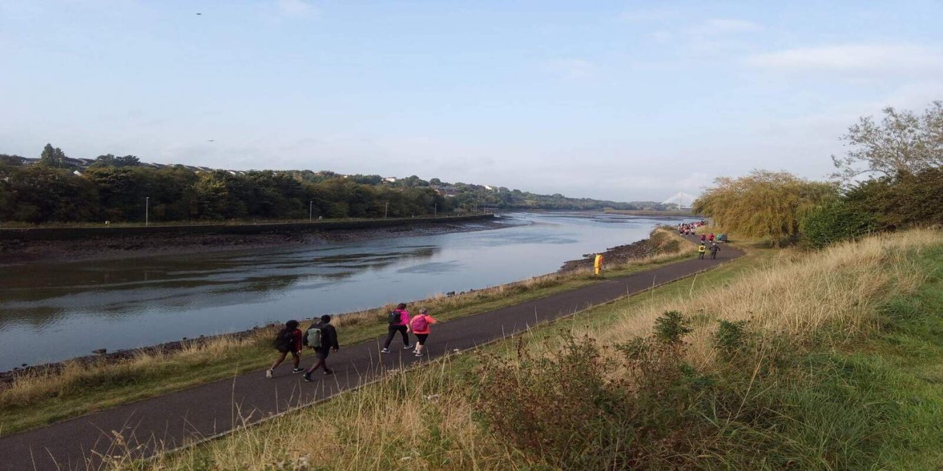 failte Ireland, Boyne Valley Blue valley river beside a grey path with green and beige grass and hay along the side of the path.