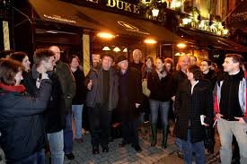 crowd of people standing outside of a pub 