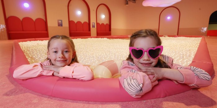Dream Point 1 Two young girls posing in ball pit. Girl on the right is wearing pink sunglasses
