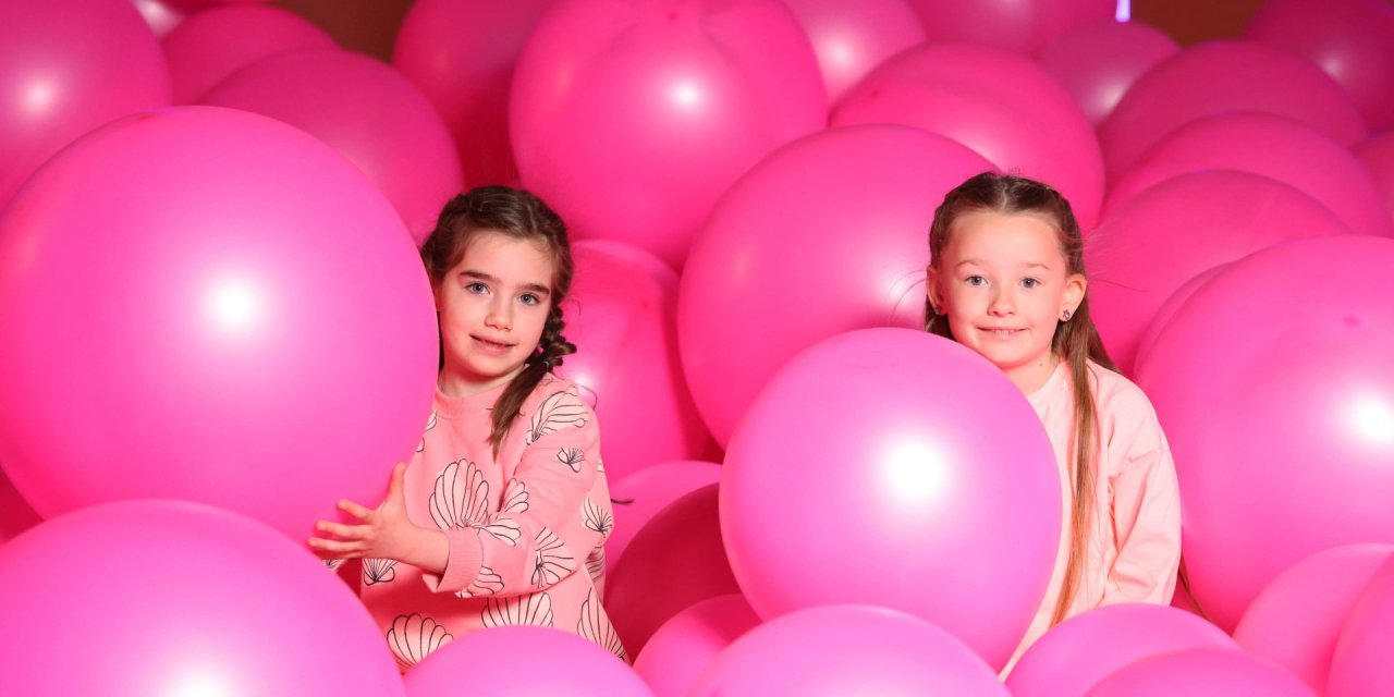 Two young girls playing surrounding by pink inflatables 