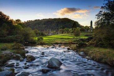 Flowing river with Glendalough round tower and wicklow national park