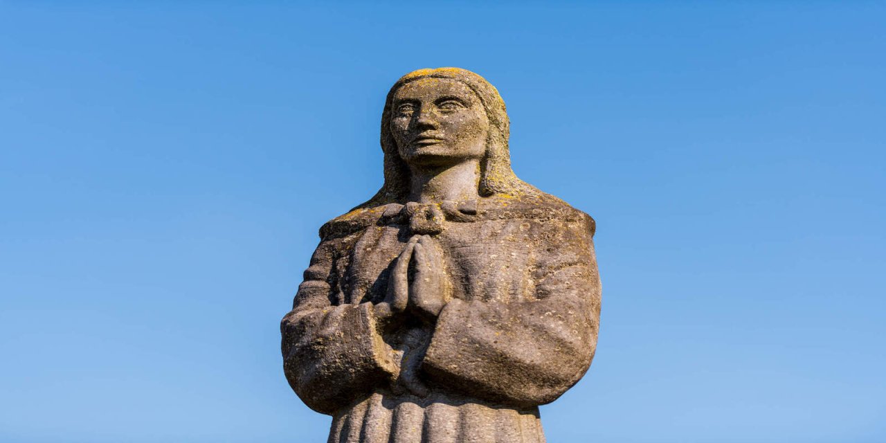 statue of a women with her palms pressed together saying a prayer