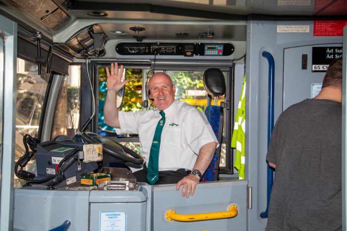 bus driver sitting down at drivers seat and is waving 