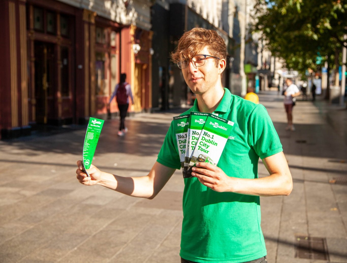 man with glasses standing on street with brochures in hand 
